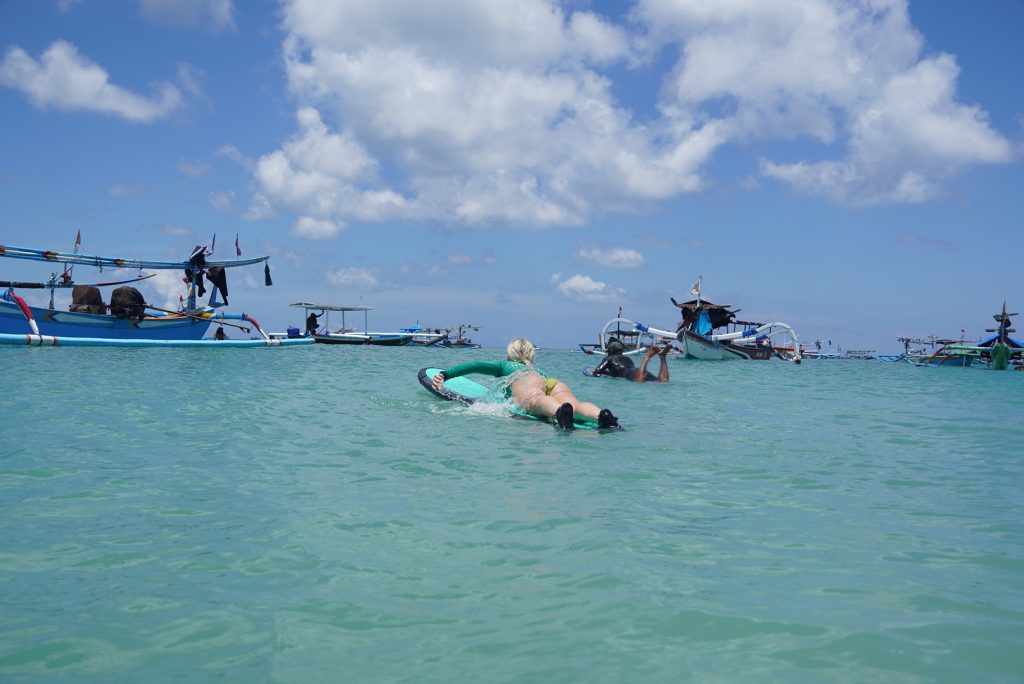 A traditional boat heading towards the offshore baby reef sanur surf spot during clean wet season conditions.