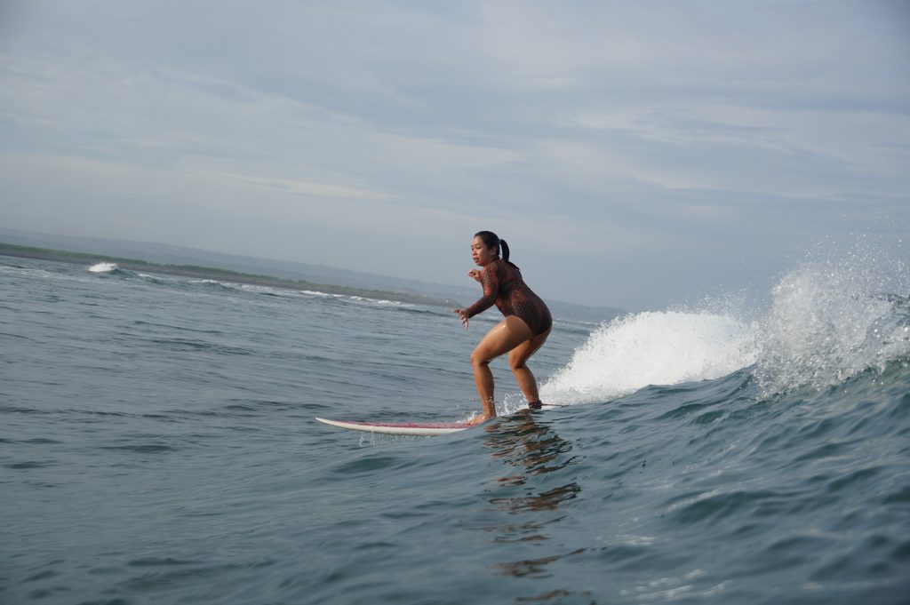 Kuta Reef (Kuta) - Surf Journey Bali Woman standing on surfboard at perfect reef for beginner at Kuta Reef (Kuta) with Surf Journey Bali