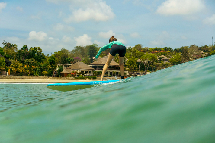 Nusa dua surf lessons - Surf Journey Bali A happy beginner enjoying premium nusa dua surf lessons on a sunny day.