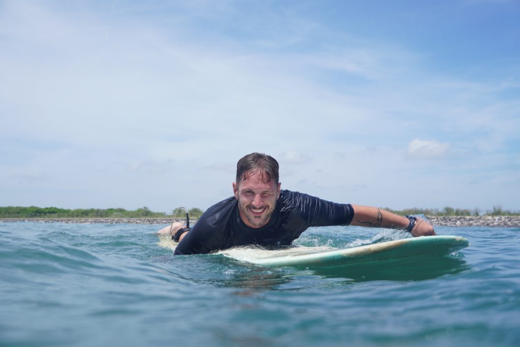 Top beginner surf spots uluwatu - Surf Journey Bali A novice enjoying safe, friendly waves at Thomas Beach, one of the top beginner surf spots uluwatu.